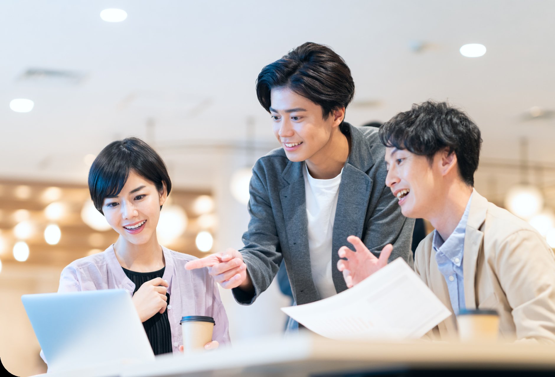 ノートパソコンを囲んで話す3人の若手社員